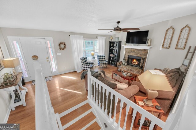 2006 Carrollton Hwy, Temple, GA 30179 - living area featuring light wood-style floors, a stone fireplace, ceiling fan, and baseboards