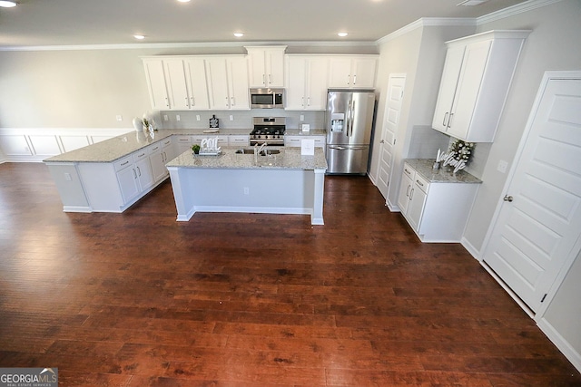 2304 Shetley Creek Dr, Norcross, GA 30071 - kitchen featuring appliances with stainless steel finishes, ornamental molding, a peninsula, light stone countertops, and a kitchen island with sink