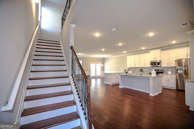 2304 Shetley Creek Dr, Norcross, GA 30071 - kitchen with appliances with stainless steel finishes, a center island with sink, dark wood-style flooring, crown molding, and white cabinetry