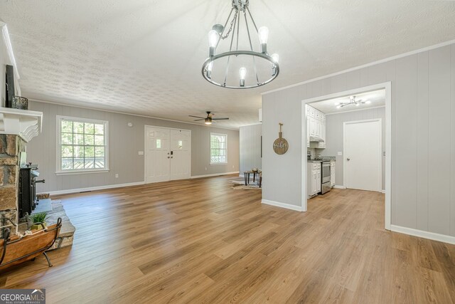 130 April Trce, Dawsonville, GA 30534 - unfurnished living room with a chandelier, light wood finished floors, a ceiling fan, crown molding, and baseboards