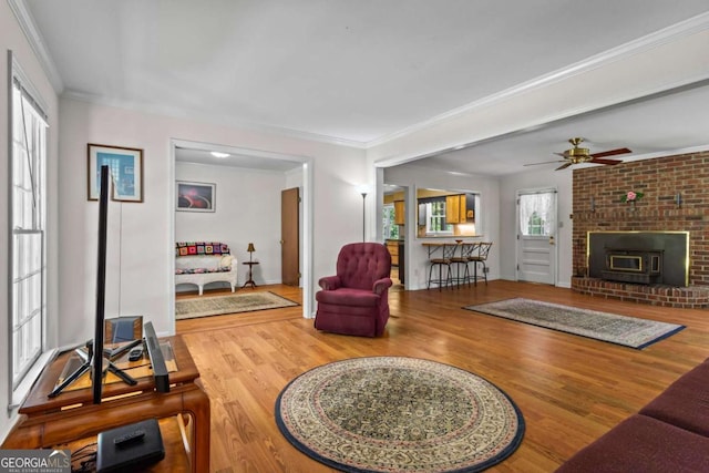 8415 Ridge Rd, Fairburn, GA 30213 - living room featuring wood finished floors, a brick fireplace, ceiling fan, and crown molding