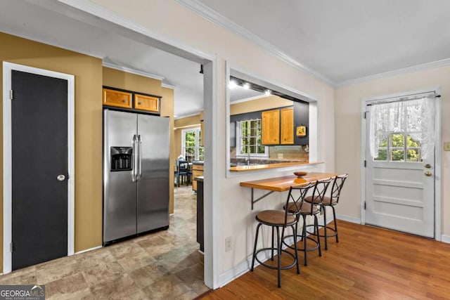 8415 Ridge Rd, Fairburn, GA 30213 - kitchen featuring stainless steel refrigerator with ice dispenser, crown molding, brown cabinetry, and healthy amount of natural light