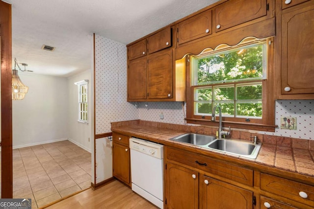 2617 Laurel Woods Ln SE, Conyers, GA 30094 - kitchen with white dishwasher, a sink, brown cabinetry, baseboards, and wallpapered walls