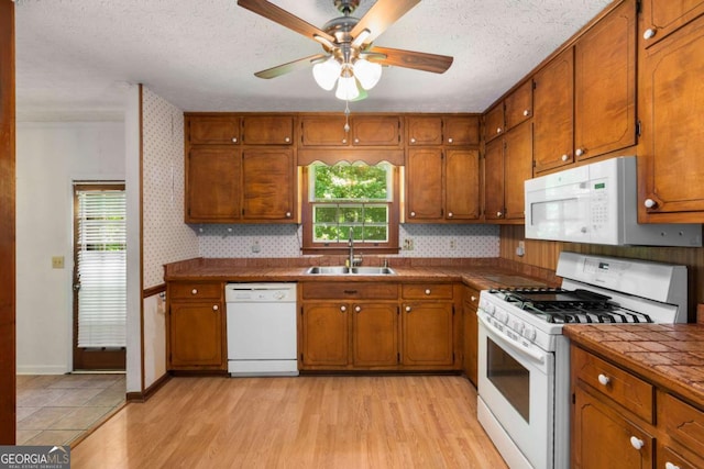 2617 Laurel Woods Ln SE, Conyers, GA 30094 - kitchen featuring white appliances, a sink, brown cabinets, and a textured ceiling