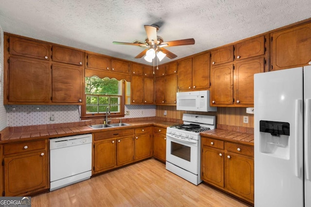 2617 Laurel Woods Ln SE, Conyers, GA 30094 - kitchen featuring white appliances, a sink, tile countertops, brown cabinets, and a textured ceiling