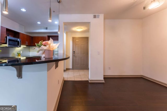 390 17th St NW Unit 2040, Atlanta, GA 30363 - kitchen with stainless steel microwave, a breakfast bar, dark countertops, hardwood / wood-style flooring, and decorative light fixtures