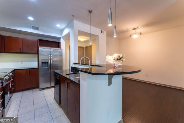 390 17th St NW Unit 2040, Atlanta, GA 30363 - kitchen featuring stainless steel appliances, dark countertops, a breakfast bar area, pendant lighting, and an island with sink