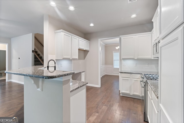 1537 Maplecliff Way, Sugar Hill, GA 30518 - kitchen with stainless steel stove, a peninsula, white cabinets, dark wood finished floors, and recessed lighting