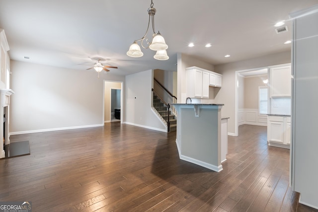 1537 Maplecliff Way, Sugar Hill, GA 30518 - kitchen featuring a ceiling fan, white cabinets, a peninsula, dark wood-style floors, and a breakfast bar