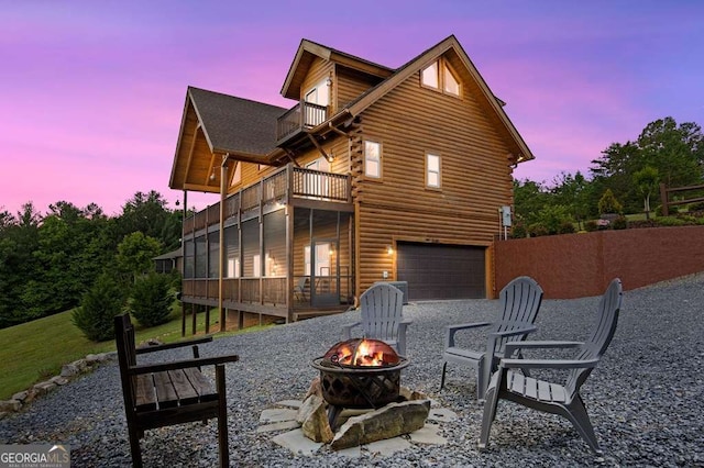 325 Emelia Dr, Morganton, GA 30560 - back of house at dusk with a balcony, a fire pit, a garage, and log siding