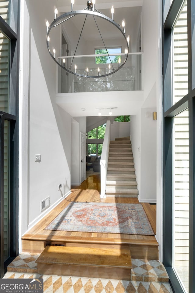425 Wagers Mill Rd, Newnan, GA 30263 - stairs with a chandelier, a towering ceiling, wood finished floors, and baseboards