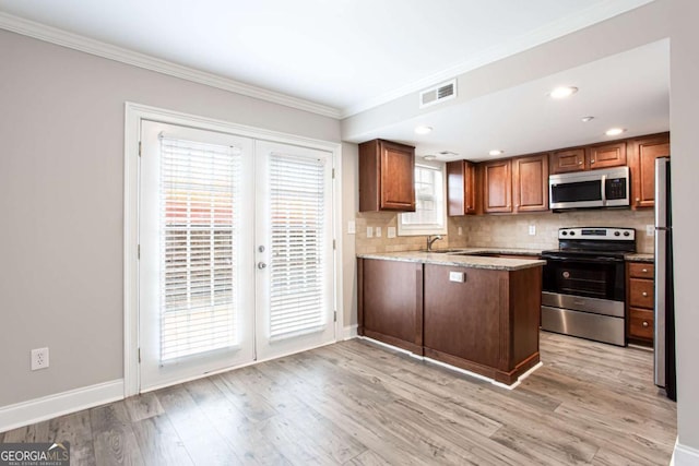 7 Villa Ct SE, Smyrna, GA 30080 - kitchen featuring appliances with stainless steel finishes, a peninsula, crown molding, decorative backsplash, and light wood finished floors