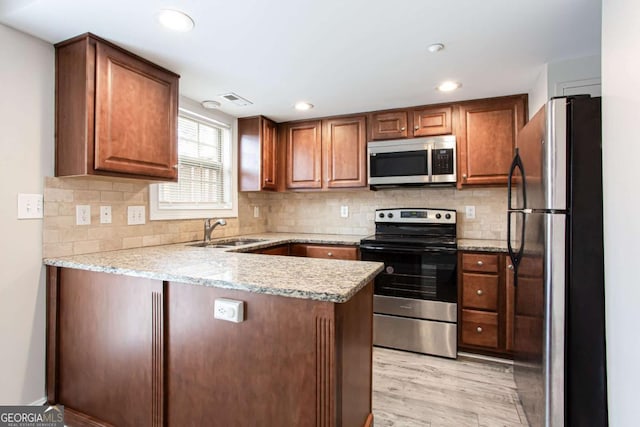 7 Villa Ct SE, Smyrna, GA 30080 - kitchen featuring appliances with stainless steel finishes, a sink, a peninsula, light wood finished floors, and backsplash