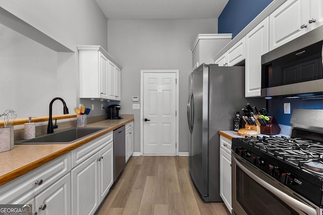 264 Baldwin Ct, Newnan, GA 30263 - kitchen featuring appliances with stainless steel finishes, white cabinetry, light wood-type flooring, light countertops, and a textured ceiling