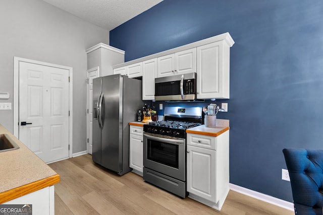 264 Baldwin Ct, Newnan, GA 30263 - kitchen with appliances with stainless steel finishes, white cabinets, light wood-style flooring, light countertops, and a textured ceiling