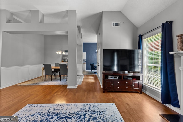 264 Baldwin Ct, Newnan, GA 30263 - living room with a chandelier, wood finished floors, vaulted ceiling, and a wainscoted wall