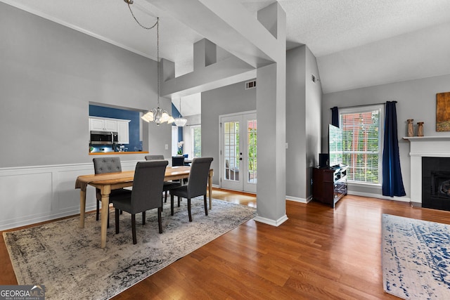 264 Baldwin Ct, Newnan, GA 30263 - dining room with french doors, a fireplace with flush hearth, wood finished floors, a chandelier, and high vaulted ceiling