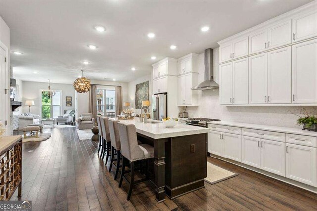 4355 Parkside Pl, Sandy Springs, GA 30342 - kitchen featuring wall chimney range hood, open floor plan, dark wood-type flooring, a breakfast bar, and white cabinetry