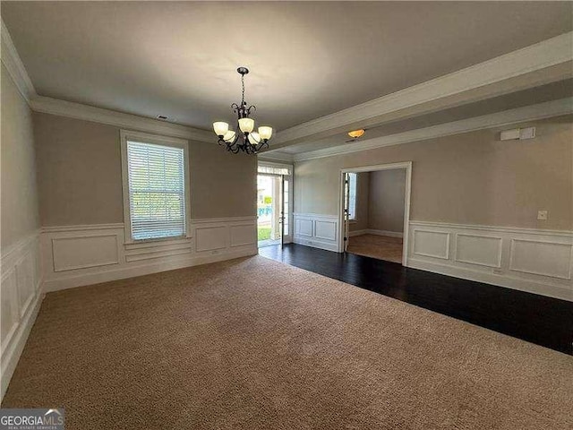 3488 Woodshade Dr, Loganville, GA 30052 - empty room with dark colored carpet, crown molding, a decorative wall, a chandelier, and a wainscoted wall