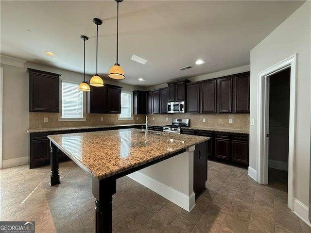 3488 Woodshade Dr, Loganville, GA 30052 - kitchen featuring appliances with stainless steel finishes, a sink, tasteful backsplash, a center island with sink, and recessed lighting