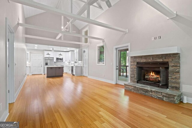 532 Coffee Cove Dr, Jasper, GA 30143 - unfurnished living room featuring high vaulted ceiling, a stone fireplace, baseboards, light wood-type flooring, and a sink