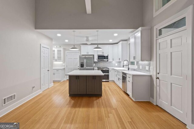 532 Coffee Cove Dr, Jasper, GA 30143 - kitchen with appliances with stainless steel finishes, tasteful backsplash, a kitchen island, light countertops, and light wood-type flooring