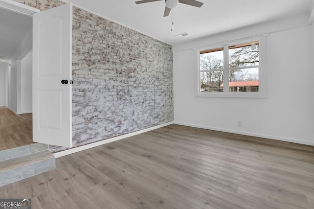 2030 Euclid St, Statham, GA 30666 - spare room featuring ceiling fan, wallpapered walls, wood finished floors, and an accent wall