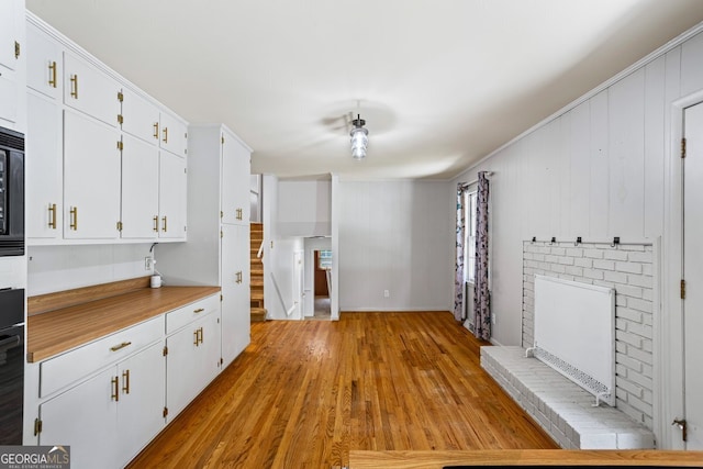 7121 Forest Dr SE, Covington, GA 30014 - unfurnished living room with light wood-type flooring, radiator, and stairway