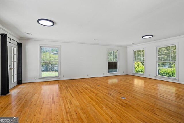 7121 Forest Dr SE, Covington, GA 30014 - unfurnished living room with ornamental molding, light wood finished floors, and plenty of natural light
