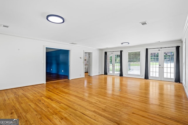 7121 Forest Dr SE, Covington, GA 30014 - spare room with french doors, ornamental molding, and light wood-style flooring