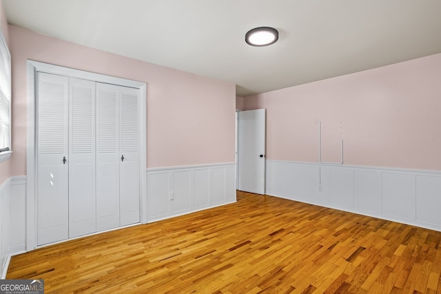 7121 Forest Dr SE, Covington, GA 30014 - unfurnished bedroom featuring light wood-type flooring, a wainscoted wall, and a closet