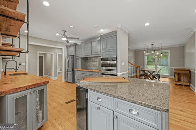 2230 Ewing Chapel Rd, Dacula, GA 30019 - kitchen featuring appliances with stainless steel finishes, gray cabinetry, crown molding, beverage cooler, and light wood finished floors