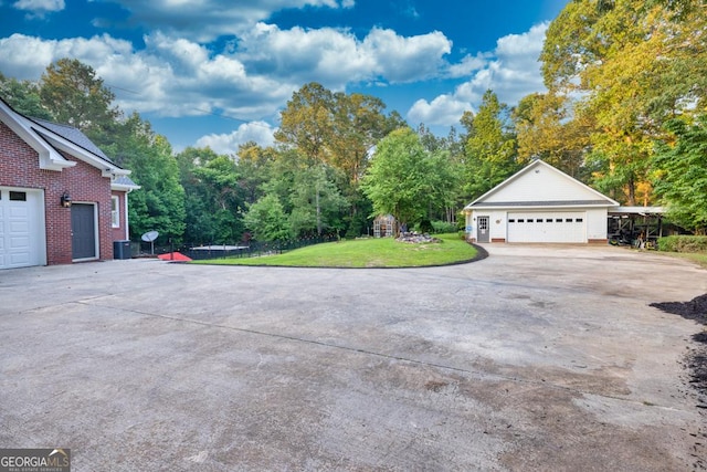 2230 Ewing Chapel Rd, Dacula, GA 30019 - view of side of property featuring a lawn, a detached garage, brick siding, and view of wooded area