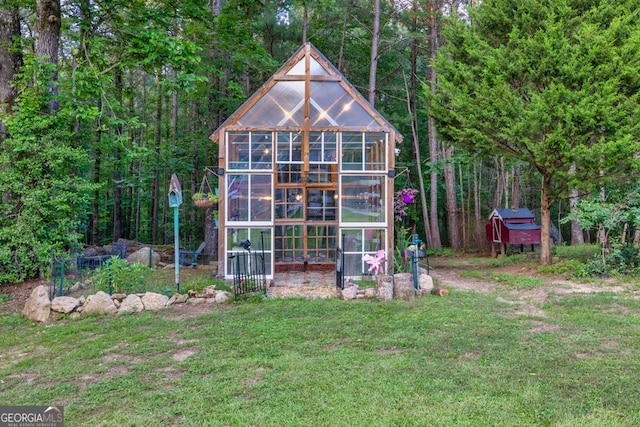 2230 Ewing Chapel Rd, Dacula, GA 30019 - back of house featuring a greenhouse, an outdoor structure, a yard, and a view of trees