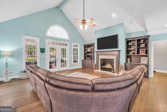 704 Branchview Ct, Mcdonough, GA 30252 - living area with a stone fireplace, light wood-type flooring, a ceiling fan, high vaulted ceiling, and baseboards