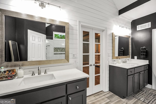 704 Branchview Ct, Mcdonough, GA 30252 - bathroom with french doors, two vanities, a tile shower, wood walls, and wood finished floors