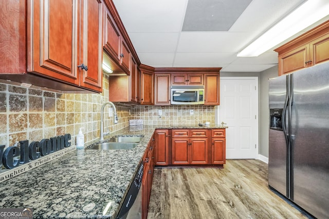 704 Branchview Ct, Mcdonough, GA 30252 - kitchen featuring appliances with stainless steel finishes, a sink, stone countertops, light wood-style floors, and decorative backsplash