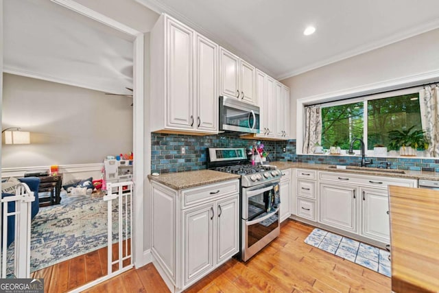 2346 Unicoi Ct, Duluth, GA 30097 - kitchen with stainless steel appliances, crown molding, a sink, light wood finished floors, and backsplash