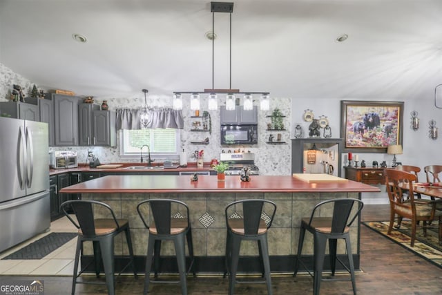287 Napier Dr, Eatonton, GA 31024 - kitchen featuring appliances with stainless steel finishes, a sink, a breakfast bar, dark wood finished floors, and dark countertops