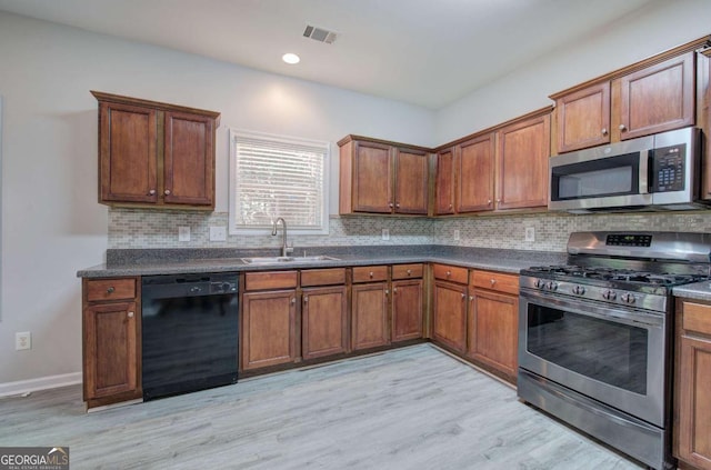 26 Ivey Meadow Dr, Dallas, GA 30132 - kitchen with appliances with stainless steel finishes, a sink, dark countertops, light wood-style floors, and decorative backsplash