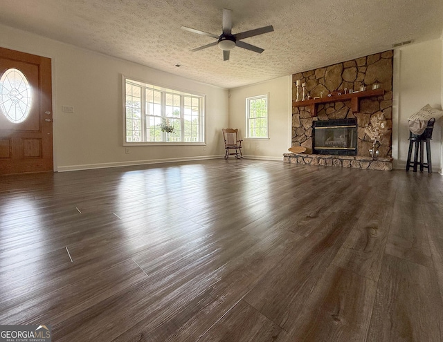 712 Boy Scout Rd, Newnan, GA 30263 - unfurnished living room with a ceiling fan, dark wood-style floors, a textured ceiling, a stone fireplace, and baseboards