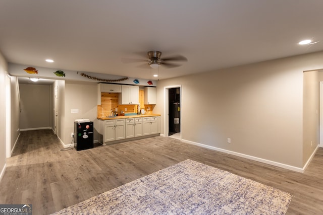 632 Creekside Trce, Covington, GA 30014 - unfurnished living room featuring baseboards, light wood finished floors, recessed lighting, a ceiling fan, and bar with sink