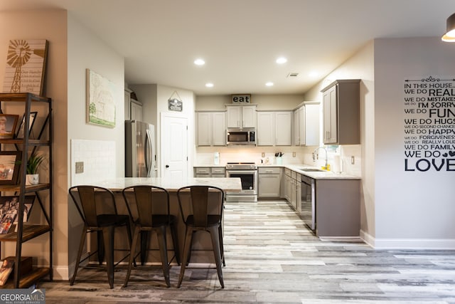 632 Creekside Trce, Covington, GA 30014 - kitchen with appliances with stainless steel finishes, a peninsula, a sink, light wood-type flooring, and tasteful backsplash
