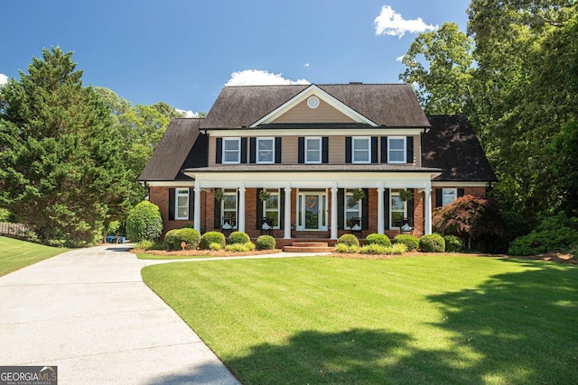 395 Grove Ridge Dr, Loganville, GA 30052 - colonial house featuring covered porch, a front yard, and brick siding