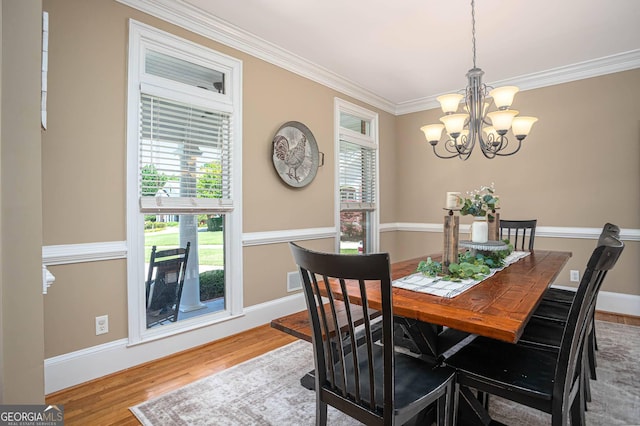 395 Grove Ridge Dr, Loganville, GA 30052 - dining area featuring a chandelier, ornamental molding, healthy amount of natural light, wood finished floors, and baseboards