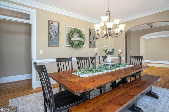 395 Grove Ridge Dr, Loganville, GA 30052 - dining space featuring arched walkways, wood finished floors, crown molding, a chandelier, and baseboards