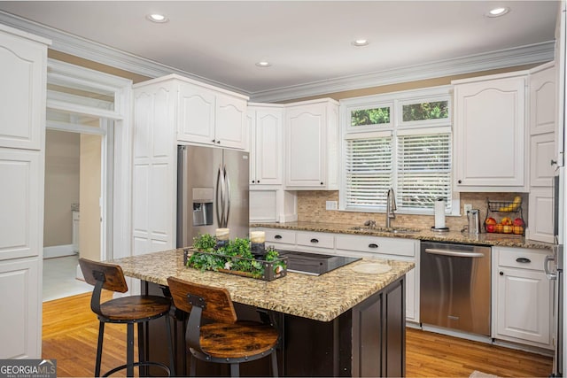 395 Grove Ridge Dr, Loganville, GA 30052 - kitchen with appliances with stainless steel finishes, a sink, white cabinetry, a breakfast bar, and crown molding