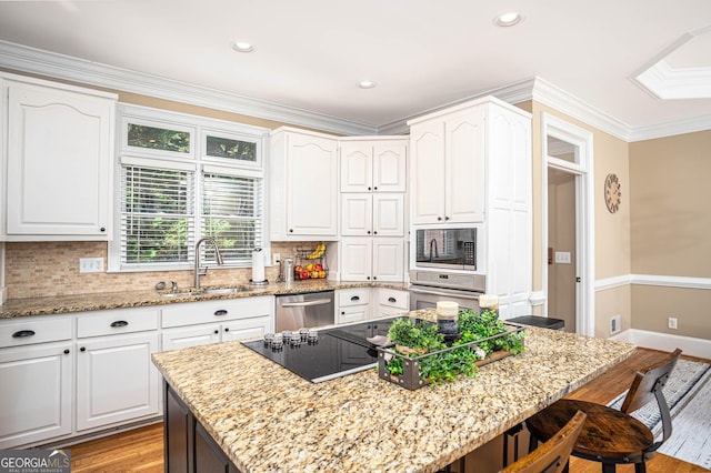 395 Grove Ridge Dr, Loganville, GA 30052 - kitchen with a sink, a kitchen bar, black appliances, light wood-style floors, and light stone countertops