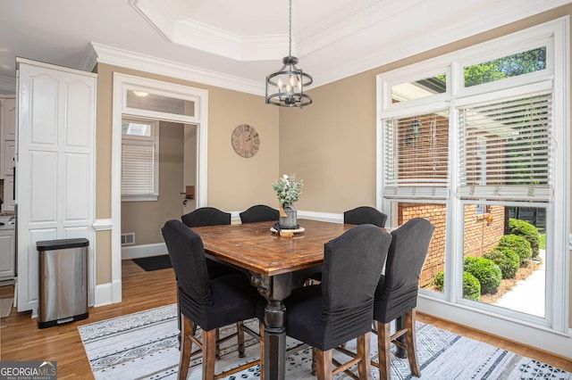 395 Grove Ridge Dr, Loganville, GA 30052 - dining space featuring plenty of natural light, a chandelier, light wood finished floors, ornamental molding, and a raised ceiling