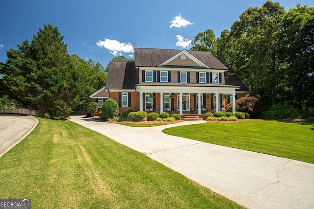 395 Grove Ridge Dr, Loganville, GA 30052 - colonial house featuring a porch, a front lawn, and brick siding